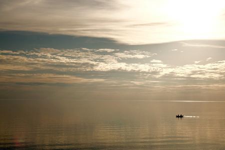 A small boat floats on the sea. Complete calm.の写真素材