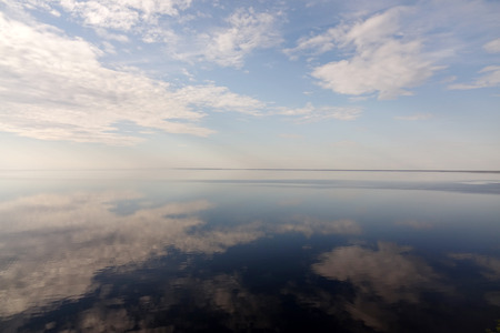 Blue sky with clouds reflection in water, for designの写真素材