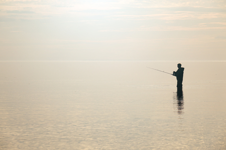 Silhouette of a fisherman at sunset. Fishing on the lake. hobby.の写真素材