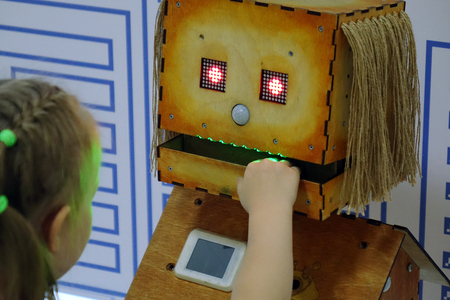 The girl touches the hand of a wooden robot. Technology.の写真素材