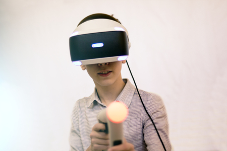 Boy using VR glasses and headset plays computer games.の写真素材