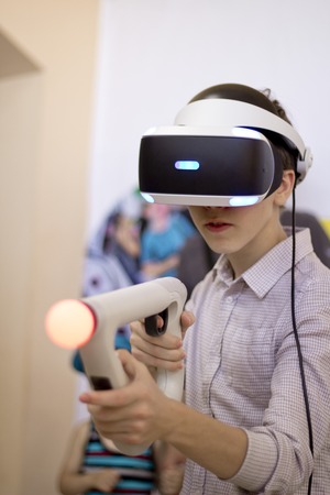 Boy using VR glasses and headset plays computer games. Virtual game.の写真素材
