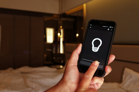 Smart Home: Man Controlling Lights With App On His Phoneの写真素材
