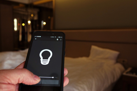 Smart Home: Man Controlling Lights With App On His Phoneの写真素材