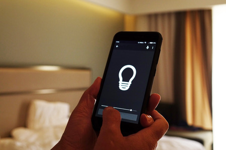 Smart Home: Man Controlling Lights With App On His Phoneの写真素材