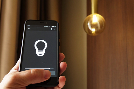 Smart Home: Man Controlling Lights With App On His Phoneの写真素材