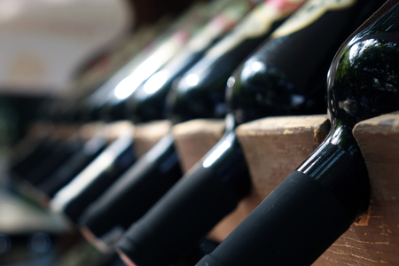 Bottles of red wine on a wooden shelfの写真素材
