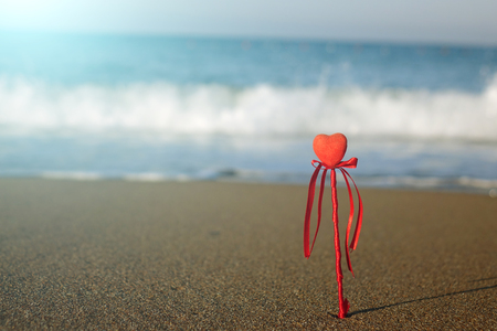 Valentine's day greeting card concept, red heart on pristine sandy beach, honeymoon vacation background.の写真素材