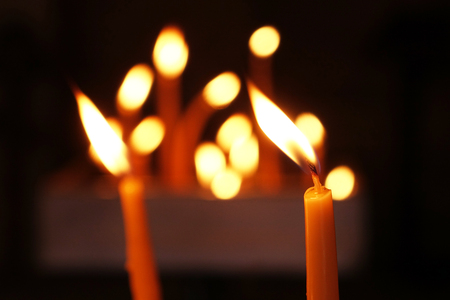 Several tall candles lit in a dark room in church