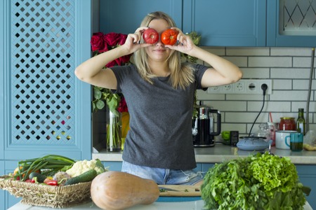 The girl is preparing healthy food in the kitchen with vegetables. Vegetarian cuisine. Having fun in the kitchen. A young Caucasian in his twenties.The concept of healthy eating.の写真素材