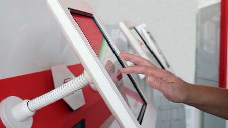 A woman touches the touch screen of a self-service device at the station. The modern concept of technologyの写真素材