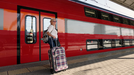 Woman traveler with Luggage arriving at the station waiting for the train. Travel concept for women.の写真素材