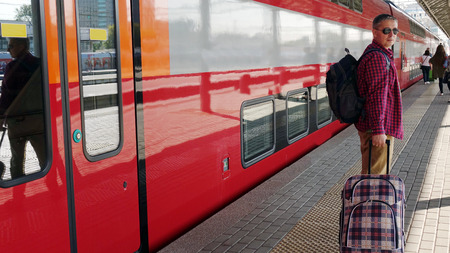 Man-traveler with Luggage at the station waiting for the departure of the train. The concept of travelling for men .の写真素材