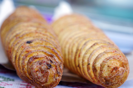 Street food. A spiral fried potato on a two sticks. Crunchy potato, Closeup.の写真素材