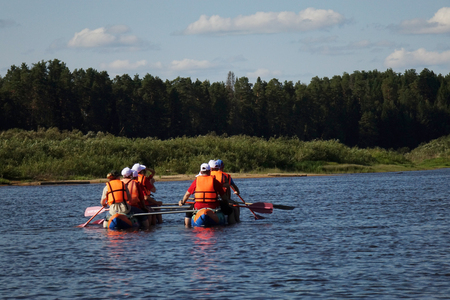 A group of tourists floating on a quiet river on inflatable catamarans, outdoor activitiesの写真素材