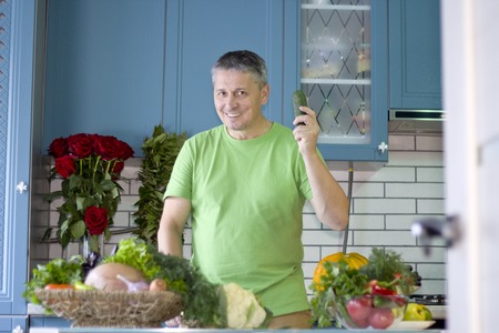 A man in the kitchen prepares vegetarian dishes.Cook standing at the kitchen table. Vegetables , ready for cooking.の写真素材