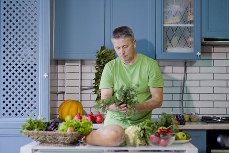 A man in the kitchen prepares vegetarian dishes. Vegetables , ready for cooking.の写真素材