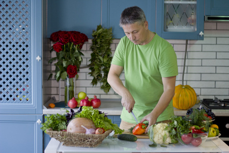 A man in the kitchen prepares vegetarian dishes.Cook standing at the kitchen table. Vegetables , ready for cooking.の写真素材
