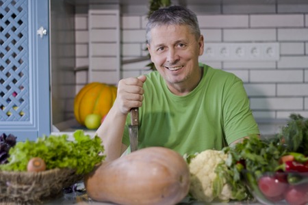 A man in the kitchen prepares vegetarian dishes. Vegetables , ready for cooking.の写真素材