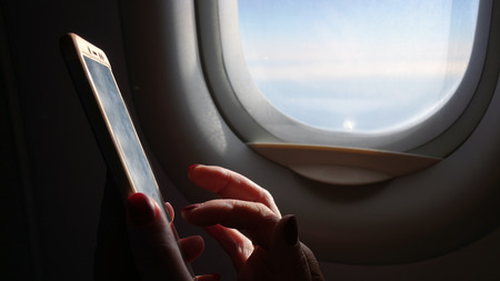 Woman on the plane working with a smartphone .Business technology and the concept of tourism ideasの写真素材