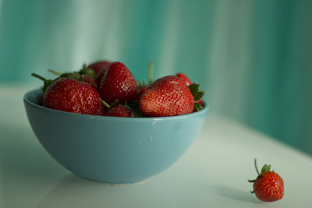Fresh strawberries in a porcelain bowl on the tableの写真素材