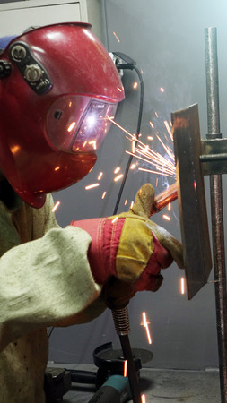 Welder in the mask. The metal product is welded by welding machineの写真素材