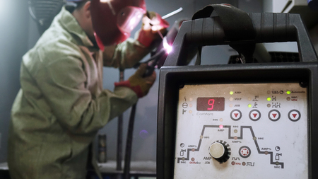Welder in the mask. The metal product is welded by welding machineの写真素材