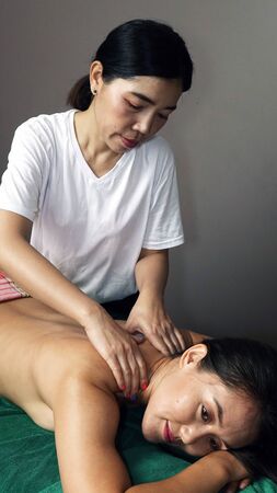 A young masseur gives a relaxing massage to a beautiful girl.の写真素材