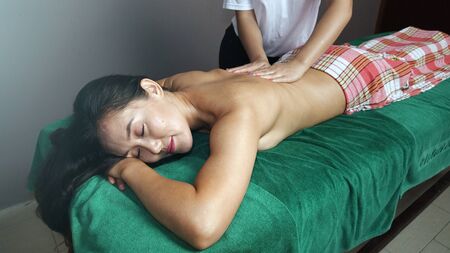 A young masseur gives a relaxing massage to a beautiful girl.の写真素材