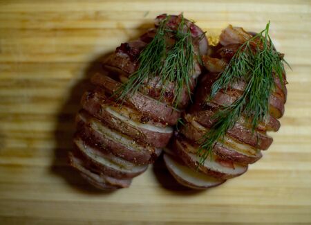 Potato accordion. Garnish potatoes stuffed with bacon and herbs on a wooden stand