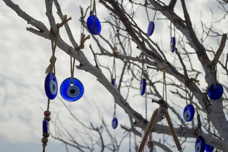 Stone in the form of a blue eye on the tree.Close-up on a tree on chains hang national signs of Turkey-Turkish eyes.の写真素材