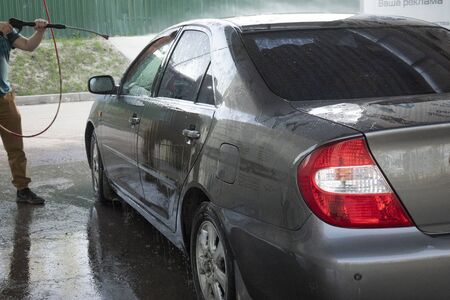 Close-up of a man washing his car with pressurized water in a car wash . Contactless car wash.の写真素材