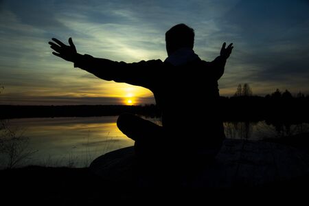 Silhouette of a man on the lake , welcoming the sunの写真素材