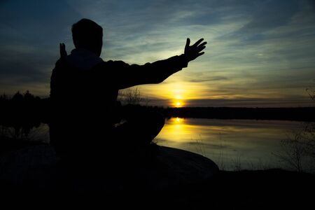 Silhouette of a man on the lake , welcoming the sunの写真素材