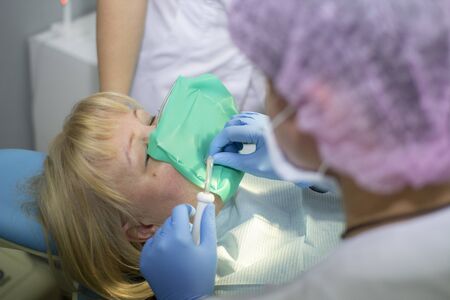 A female dentist in a white uniform examines a patient. Medicine, Dentistry, orthodontic concept.の写真素材
