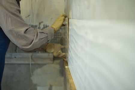 Layout of ceramic tiles on grey cement on the wall. The process of applying tiles .の写真素材