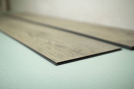 Vinyl laminate. Laying of the floor covering. A worker installing a new vinyl tile on the floorの写真素材