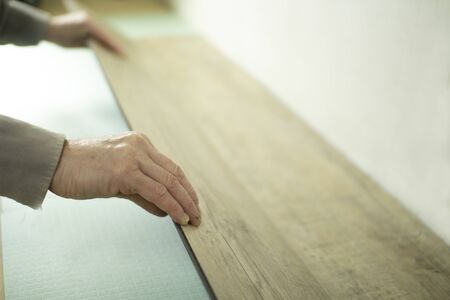 Vinyl laminate. Laying of the floor covering. A worker installing a new vinyl tile on the floorの写真素材