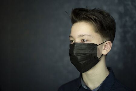 Portrait of a brown-eyed teenager in a black medical mask. Antivirus protection.の写真素材