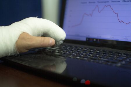 A man with a cast on his arm is working at a computer. incapacityの写真素材