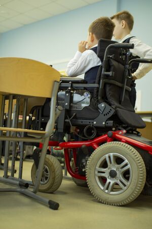 A disabled student in a wheelchair in primary school. Socialization of the individual in society.の写真素材