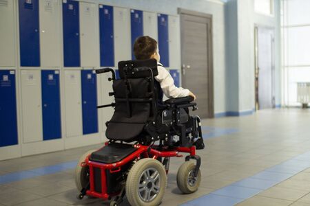 A disabled student in a wheelchair in primary school. Socialization of the individual in society.の写真素材