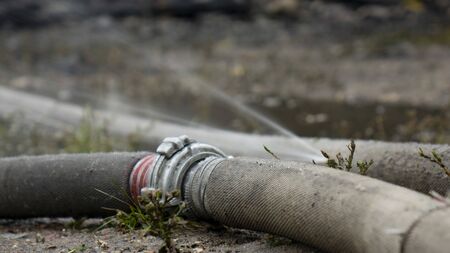 Water flows out of the hole in the fire hose.