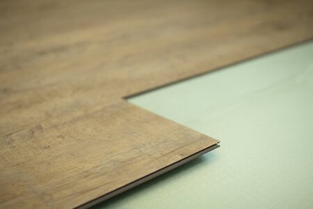 Vinyl laminate. Laying of the floor covering. A worker installing a new vinyl tile on the floorの写真素材