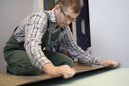 A worker puts a new laminate on the floor. Laying the floor covering. Master in the house.の写真素材