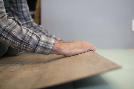 Vinyl laminate. Laying of the floor covering. A worker installing a new vinyl tile on the floor