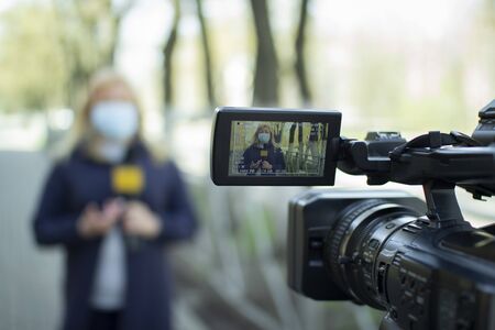 A female journalist in a protective medical mask is reporting in a deserted city.の写真素材