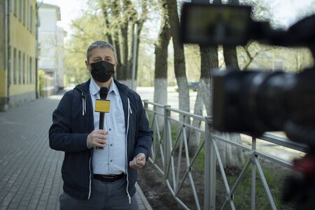 A middle- aged European journalist in a protective medical mask is reporting in a deserted city.の写真素材
