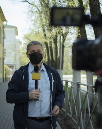 A middle- aged European journalist in a protective medical mask is reporting in a deserted city.の写真素材