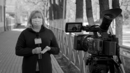 A female journalist in a protective medical mask is reporting in a deserted city.の写真素材